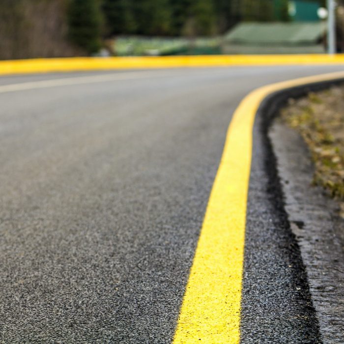 Perspective of asphalt road with yellow line on it